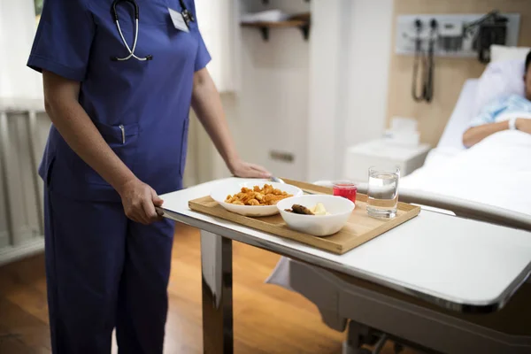 hospital-food-machines hospital food machines: a nurse puts food on a patient's tray next to the hospital bed