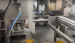 RM48 packaging machine, auto load tray sealer, pre-filled cup sealing machine, rice cup packaging, Rocket Machine Works RM48, large dial plate packaging machine, versatile sealing equipment, cup capping machine, industrial food packaging, flexible filling and sealing