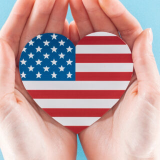 hands hold an American flag heart with a blue background